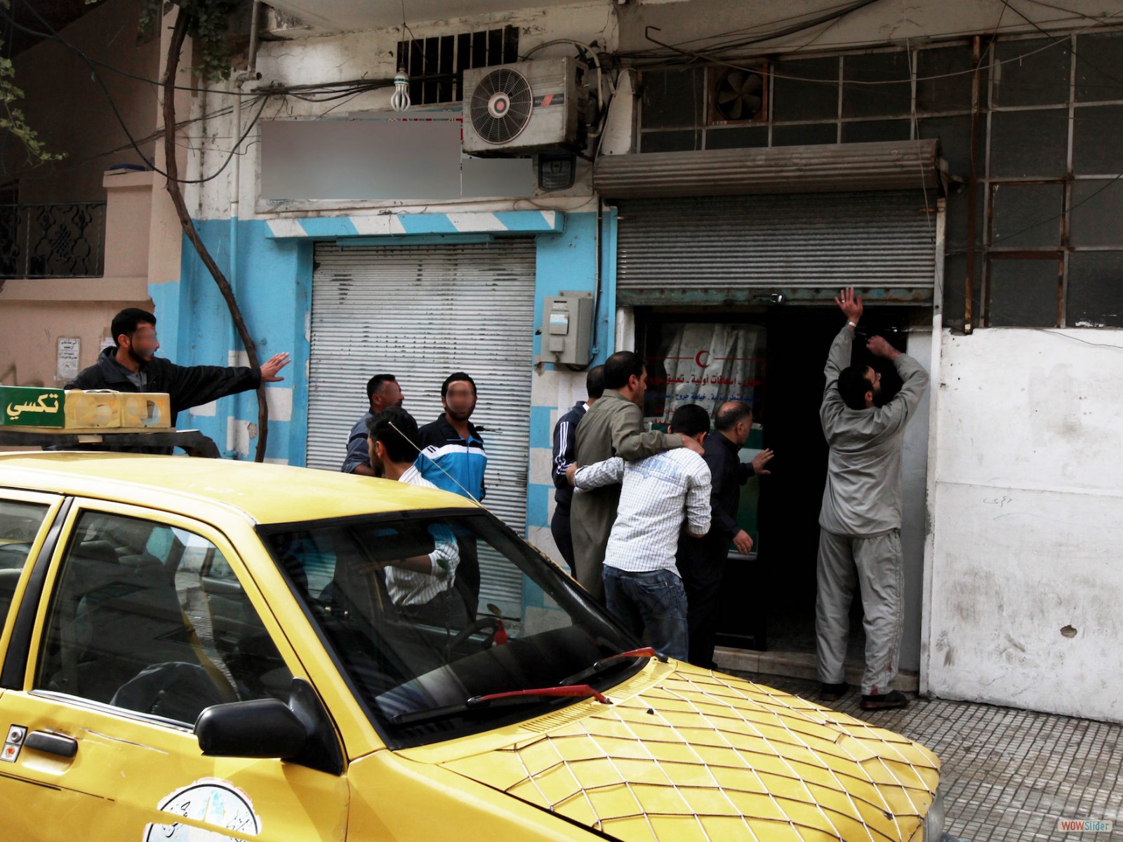 Syrie, Homs. Quartier de Khalidiyya.
Lors de la manifestation hebdomadaire du vendredi, des civils blessés sont amenés dans un dispensaire tenu secret par peur de représailles. Les visages, les enseignes des commerces ou le numéro du taxi ont été floutés à la demande de la population.
<br><b><i>

Syria, Homs, Khalidiyya neighborhood.
At the weekly demonstration on Friday, injured civilians are being taken to a medical center kept secret for fear of reprisals. The faces, shop signs and taxi number have been concealed at the request of the local community. </i></b>

