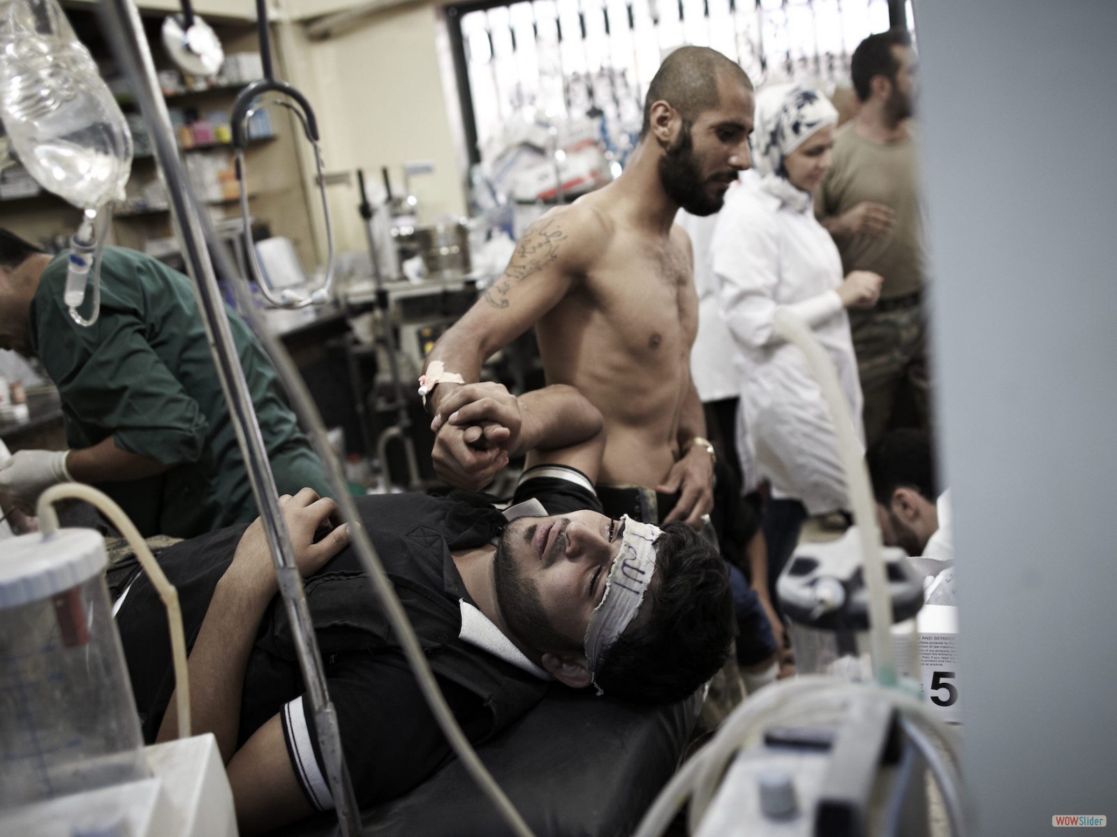 Un combattant de l’ASL tenant la main d’un camarade blessé, à l’hôpital Dar al-Shifa.
<br><i><b>

A Free Syrian Army fighter holding the hand of a wounded comrade at Dar al-Shifa hospital.
</b></i><br><i>© Sebastiano Tomada - Sipa Press - 2013</i>

