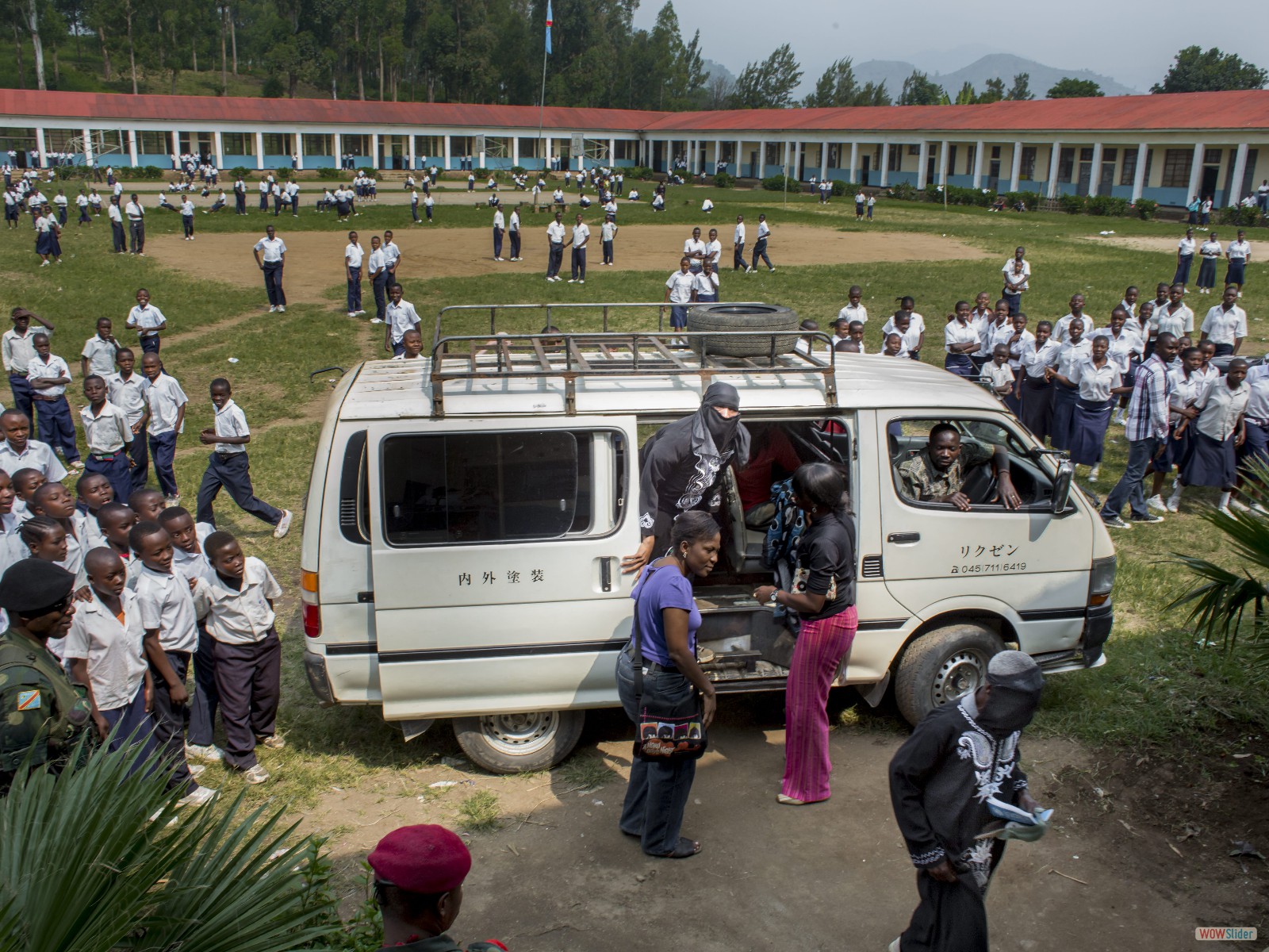 Des élèves regardent le véhicule amenant les femmes qui vont témoigner devant le tribunal installé dans l’amphithéâtre d’une école catholique à Minova.
<br><i><b>
Students observing the van transporting women to testify in the courtroom set up in the auditorium of a local Catholic school in Minova.</b></i>
