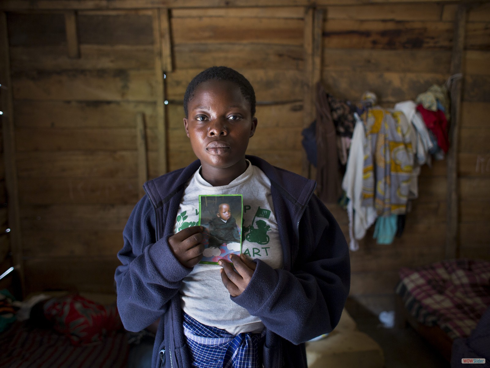 Micheline (18 ans) montre une photo de son fils Alain. Lorsque les soldats ont attaqué le refuge pour les victimes de viols où ils vivaient, Alain a été enlevé. Elle l’a retrouvé au bout de plusieurs jours : il était très malade et est décédé un mois plus tard.

Micheline, now 18, with a picture of her son, Alain. When soldiers attacked the shelter for rape survivors where they lived, Alain was abducted. It was days before she found him; he was very ill and died one month later.
